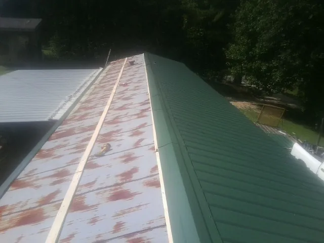 Old rusted panels beside newly installed green metal roofing — Wind Damage Roof Repair by Roofing Brothers in Lakehurst
