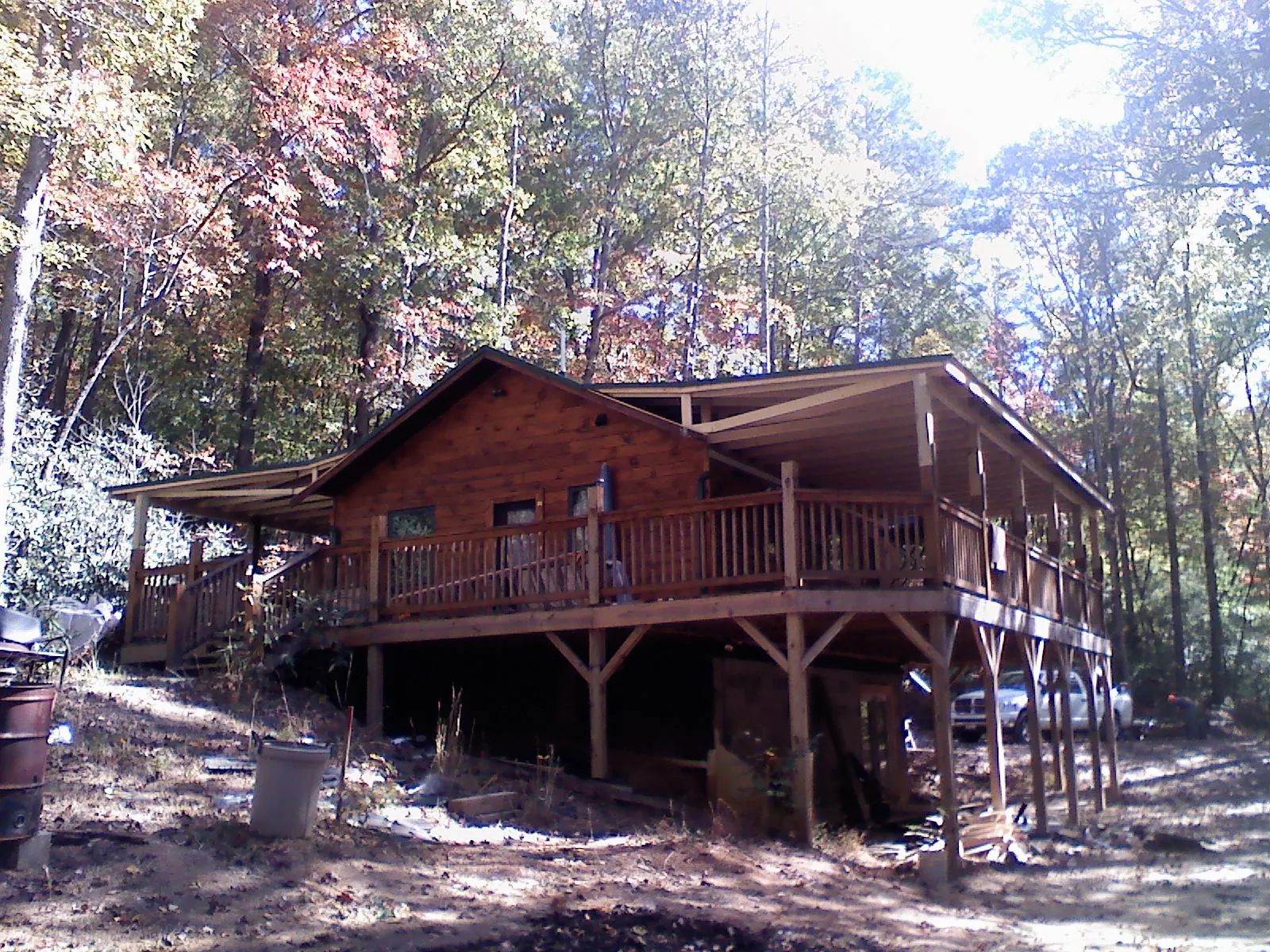 Log cabin with a wraparound porch and metal roof in the fall in Lakehurst