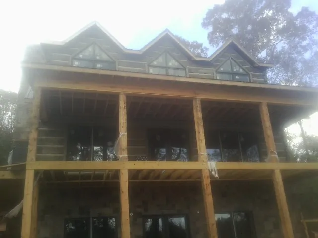 Dormers and porch framing on a large log home under construction — Roof Coating work by our crew in Lakehurst