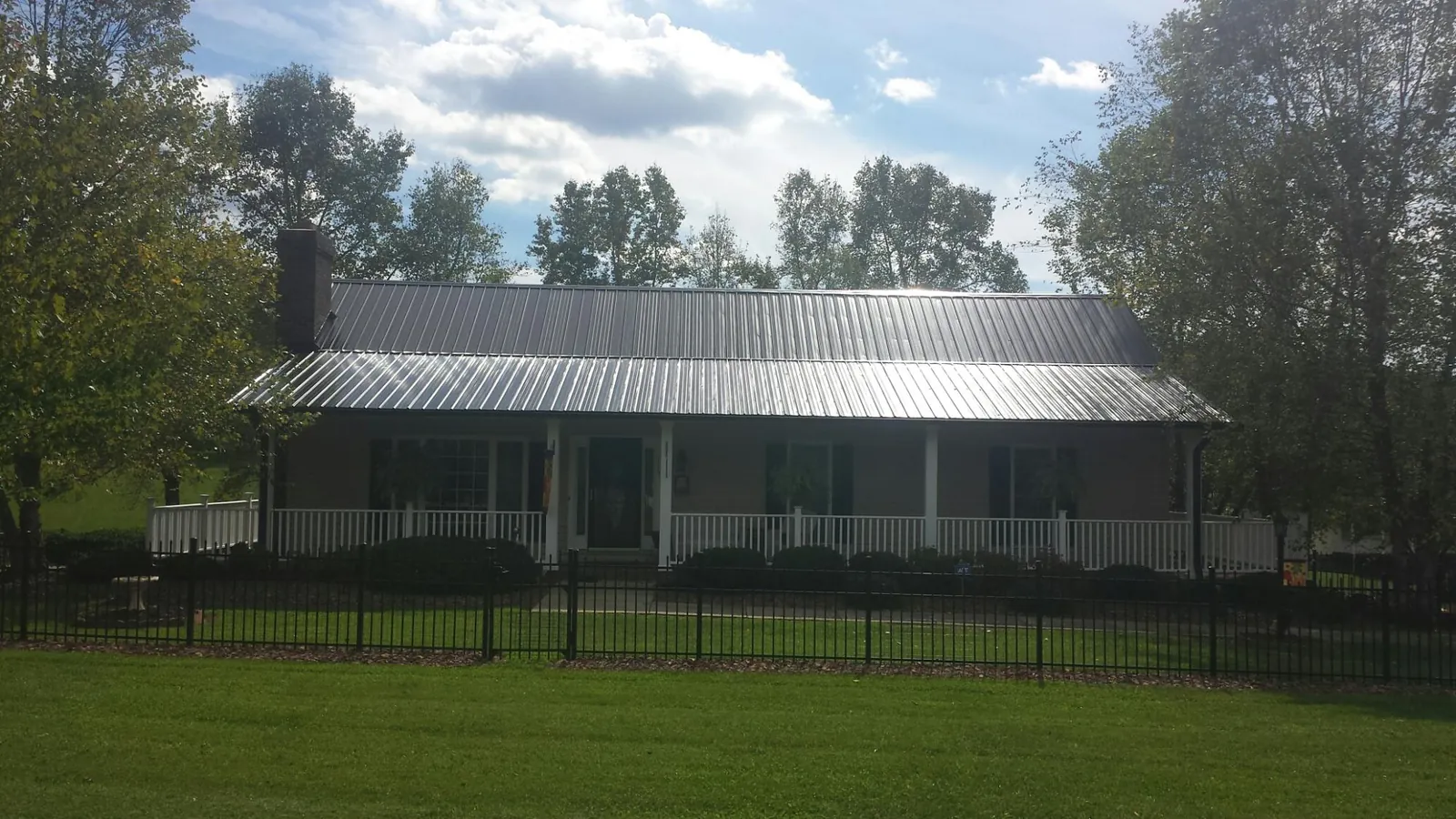 Gray metal roof on a brick ranch with a full width front porch — Gutter Guard Installation work by our crew in Lakehurst