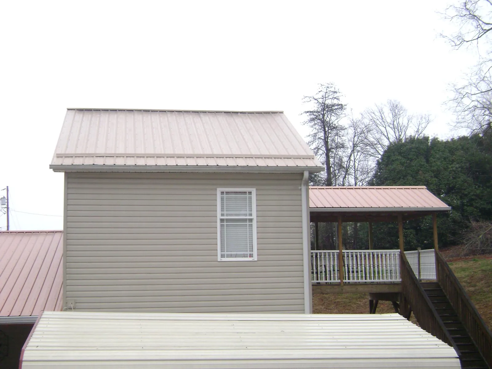 Tan metal roofs on a two story addition and attached porch, from a Roof Replacement job in Lakehurst