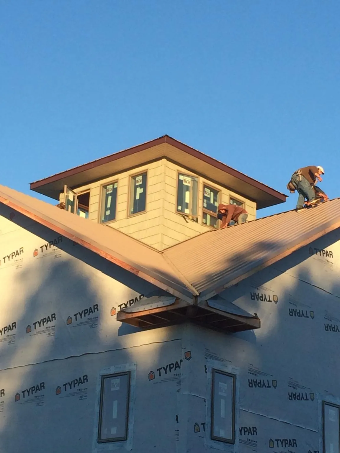 Roofers working around a rooftop cupola on a new metal roof at sunset — Roof Waterproofing in Lakehurst by Roofing Brothers